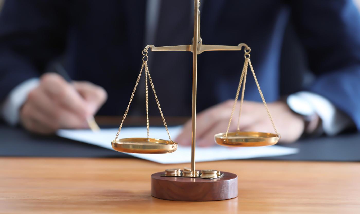 2022_Rechtsschalen op tafel in het notariskantoor met notaris op de achtergonf_Notariaat_S_777595222 2022_Rechtsschalen op tafel in het notariskantoor met notaris op de achtergonf_Notariaat_S_777595222